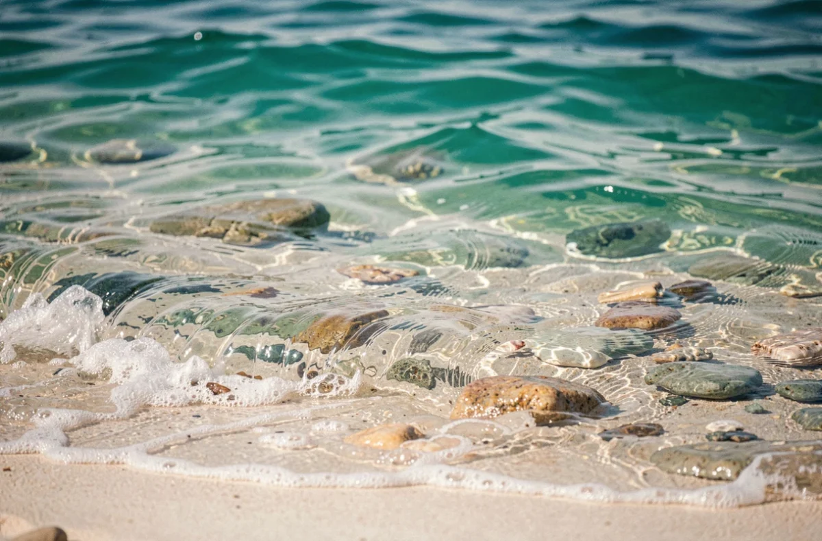 Eau turquoise aux reflets bleu-vert sur une plage de sable blanc en Méditerranée